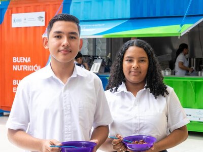 Photo: WFP/Versative/Diego Santamaria Adolescent boy and girl holding bowls of food