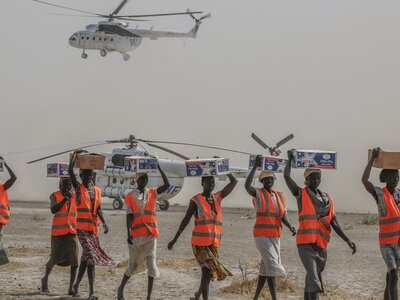 Photo: WFP/George Fominyen Women wearing vests offloading relief supplies from UN Humanitarian Air Service helicopters