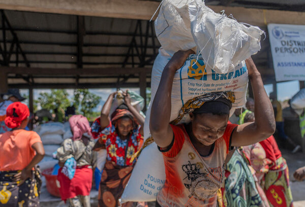 A woman carries away two WFP sacks of food assistance as others follow in DRC. Photo: WFP/Benjamin Anguandia