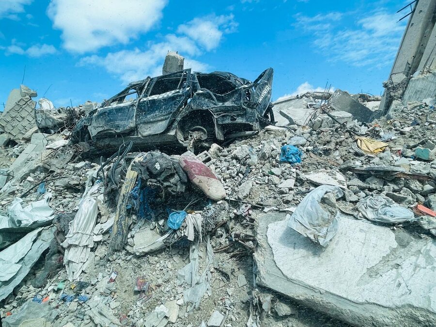 View of crushed burnt-out car atop a pile of rubble