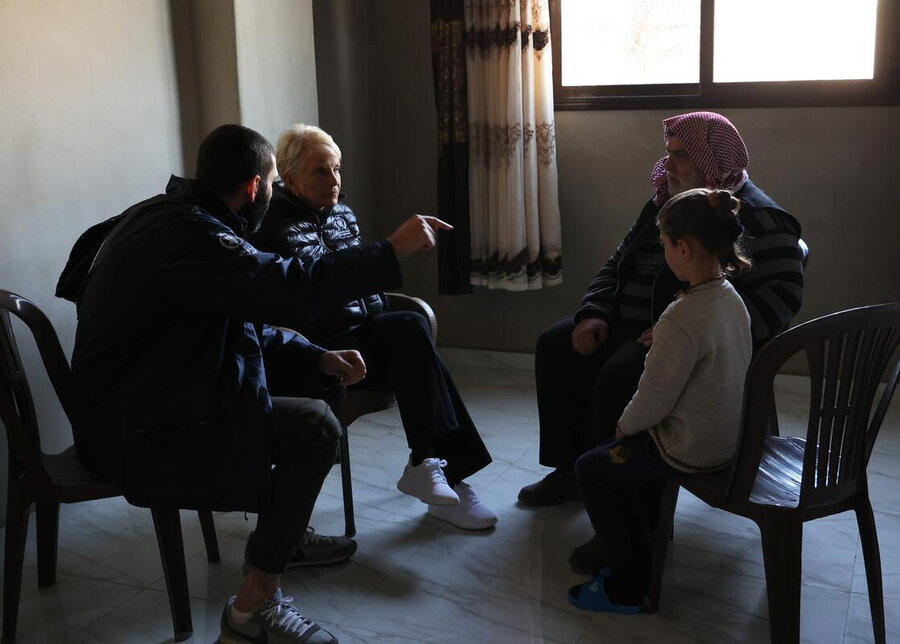 WFP Chief Cindy McCain is seat meeting a father and daughter, almost silhouetted, as an interpreter gestures