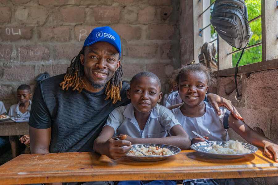 Congolese football star and WFP High-Level Supporter Distel Zola chats with  kids enjoying our school meals in the Democratic Republic of the Congo. He counts among the many people lending their voices to fight hunger. Photo: WFP/Michel Castofas