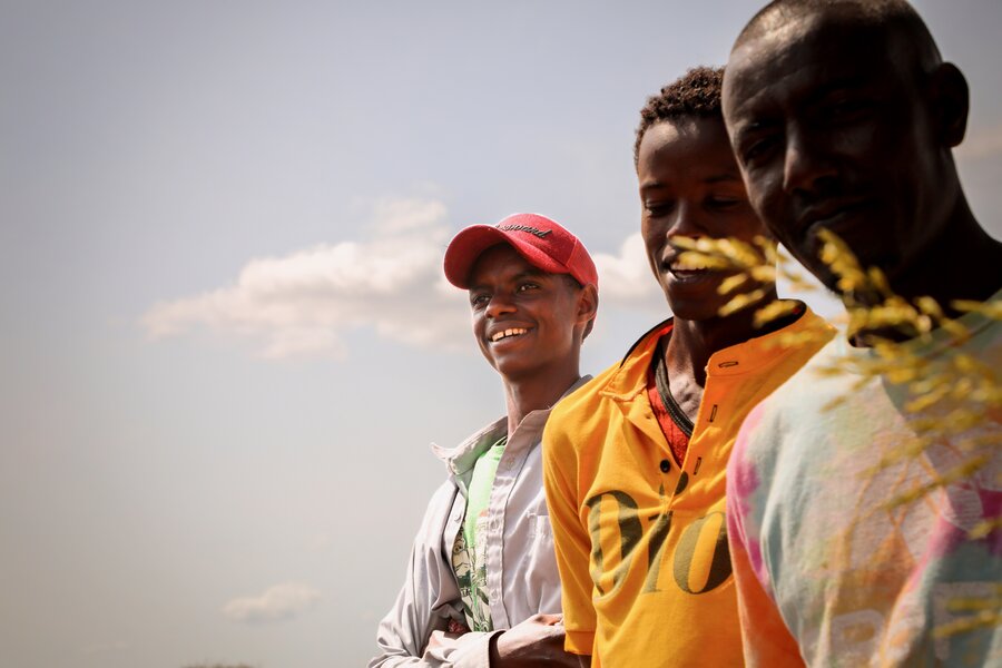 Three smiling herders backdropped by a pale blue sky. Photo: WFP/Patrick Mwangi