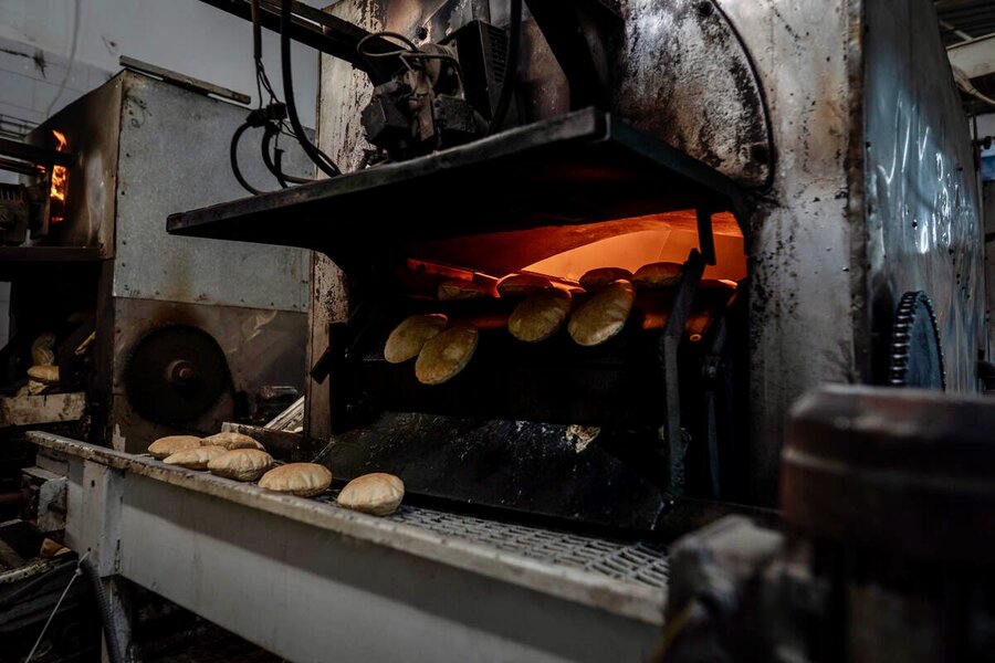 Hot loaves of pita bread falling from a fiery oven in Gaza. Photo: WFP/Maxime Le Lijour