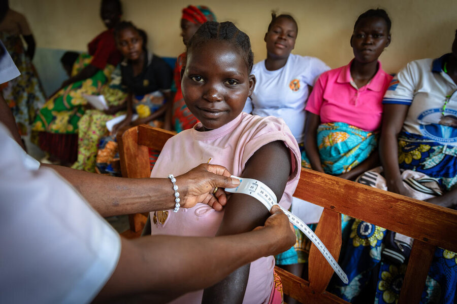 A pregnant teenager at a clinic in DRC smiles as her arm is measured