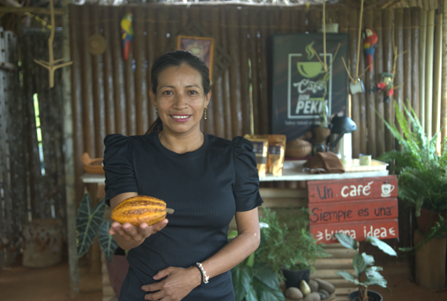 Indigenous wonan in black dress holds an orange fruit