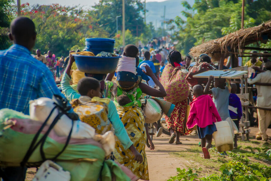 A mass of people head up a dirt road carrying their belongings. Photo: WFP/Biobei Malenga