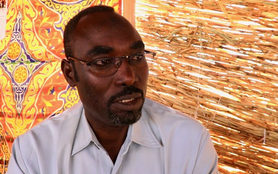 Profile of a man sporting glasses, backdropped by a bamboo walls. Photo: WFP/Petroc Wilton