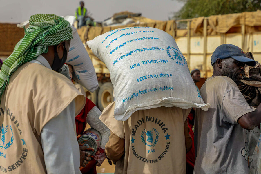 Men with WFP vests haul bags of WFP food. Photo: WFP/Arete/Salamon Djek