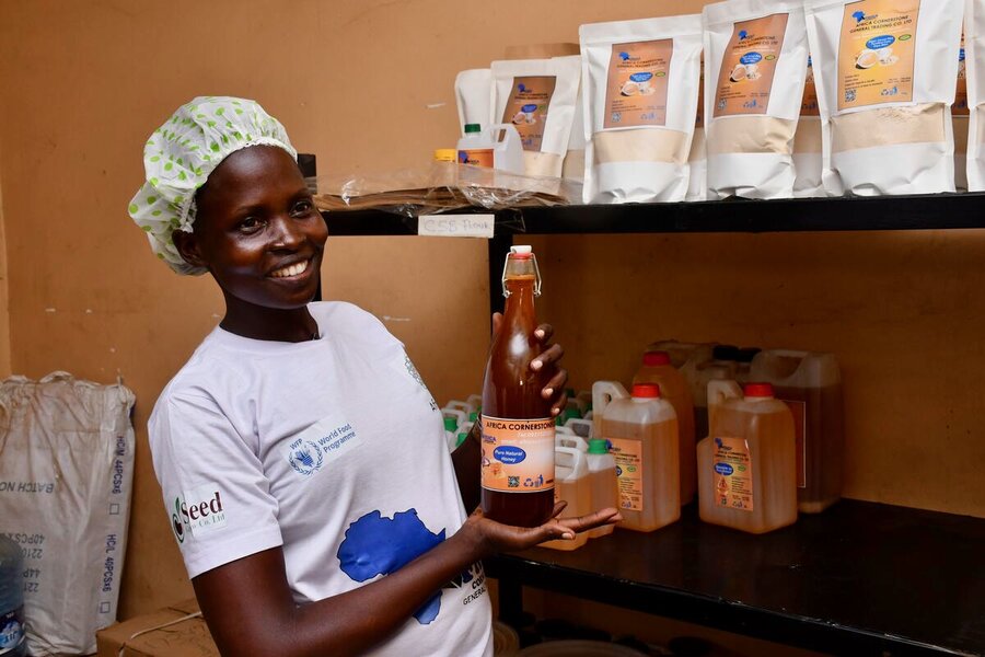 A woman in a cap and white T-shirt holds up a bottle of cooking oil.  Photo: WFP/Machrine Birungi