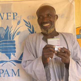An asylum seeker receiving his cash at the Nironigue relocation site in Ouangolo